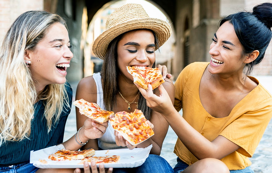 Three women eating pizza together